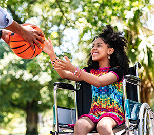 Child in a wheelchair passing a basketball