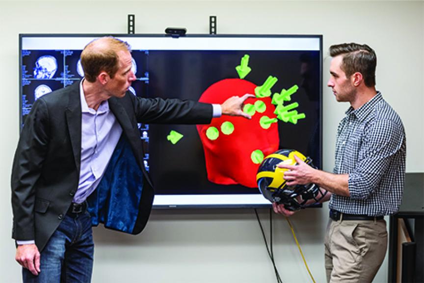 Griffen Feinberg with Concussion Center Director Steve Broglio looking at football helmet sensor map