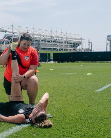 Taylor Brown stretching out a Chicago Red Stars soccer player on a training field.