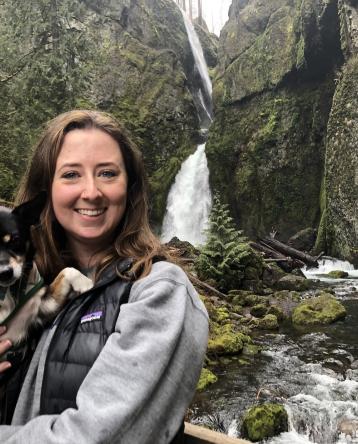 Makenzy Bennett with her Chihuahua, Miles, in front of a waterfall.