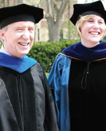 Professor Dale Ulrich and Meghann Lloyd smiling in graduation caps and gowns