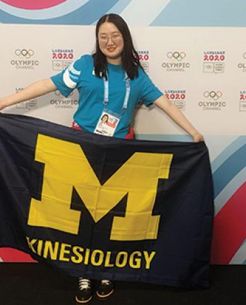 Yajie Wang holding U-M Kinesiology Flag