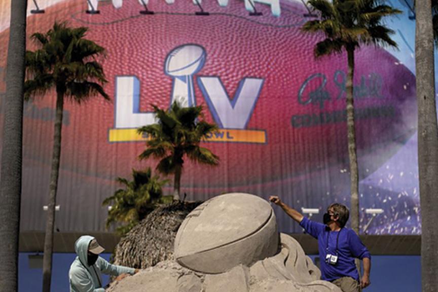 Two people building the Lombardi Trophy out of sand