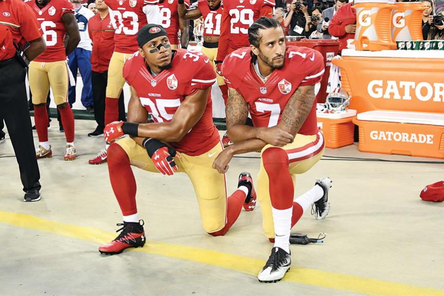 Two San Francisco 49ers players kneeling during the national anthem.
