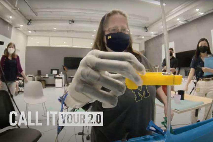 A still from the new University of Michigan PSA that shows a woman testing a prosthetic hand in a School of Kinesiology lab.