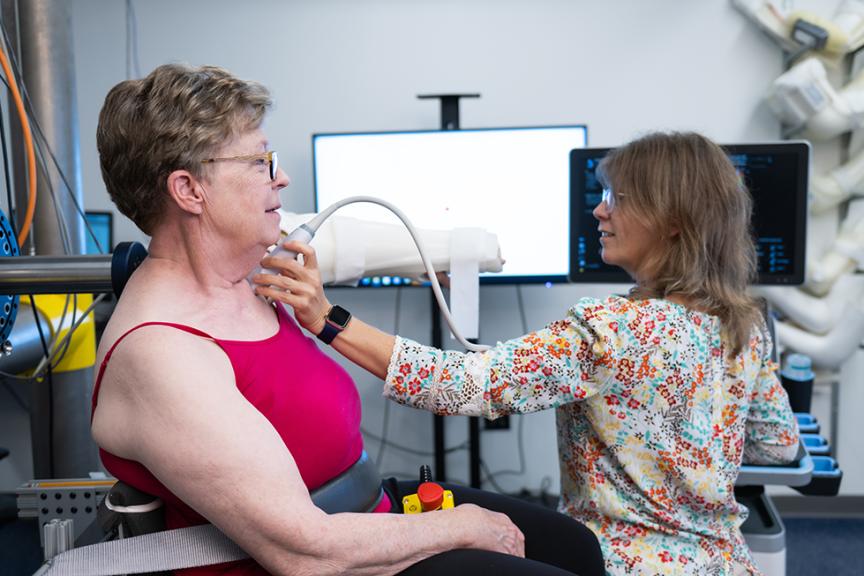 An MBIL staff member works with a participant on her arm and shoulder mobility