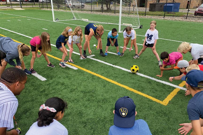 Campers forming a circle and rolling a soccer ball to each other