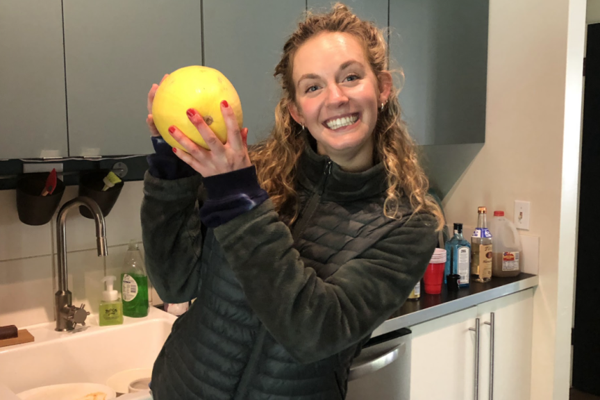 Anna Lamport stands in a kitchen holding a yellow circular vegetable.