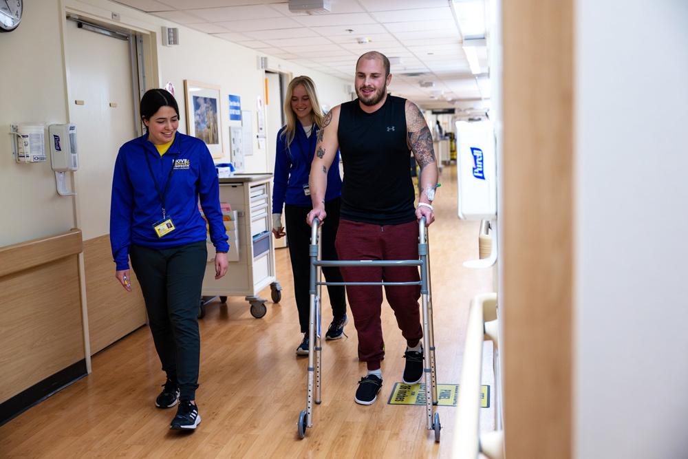 Therese Campos and Meghan Tompkins walk with a Michigan Medicine patient as part of the Mobility Initiative partnership.