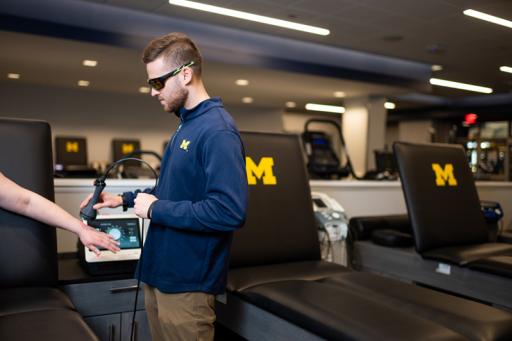 An Athletic Training student uses equipment in the Michigan Football training room