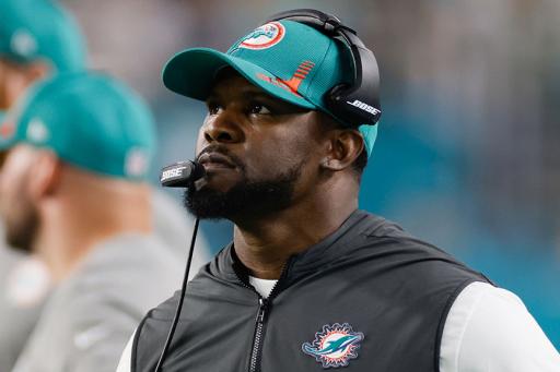 Brian Flores with headset on wearing a Miami Dolphins hat