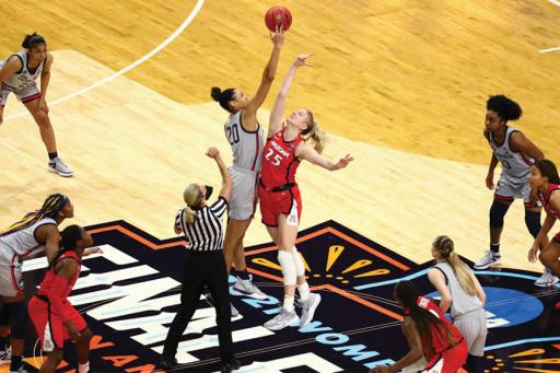 Female players in red and grey jerseys jump for a tip-off at the Women&#039;s Final Four