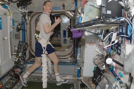 Male astronaut running on treadmill in space
