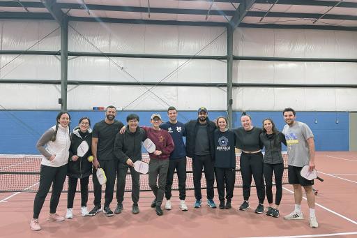 A group of graduate students gathers to take a picture after playing pickleball.