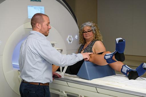 Adam Lepley, assistant professor of kinesiology , left, and Elisa Medeiros, technician, prepare a model patient for functional MRI testing