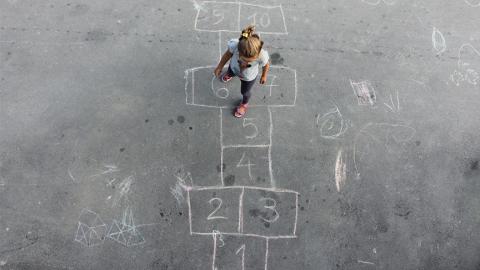Child playing hopscotch on cement