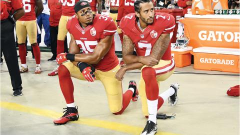 Two San Francisco 49ers players kneeling during the national anthem.