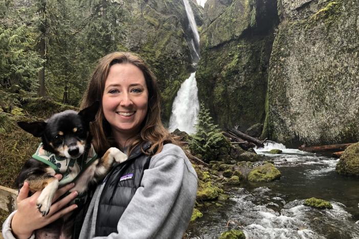 Makenzy Bennett with her Chihuahua, Miles, in front of a waterfall.